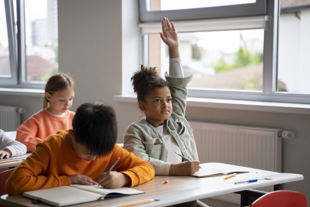 A child raising their hand in a classroom